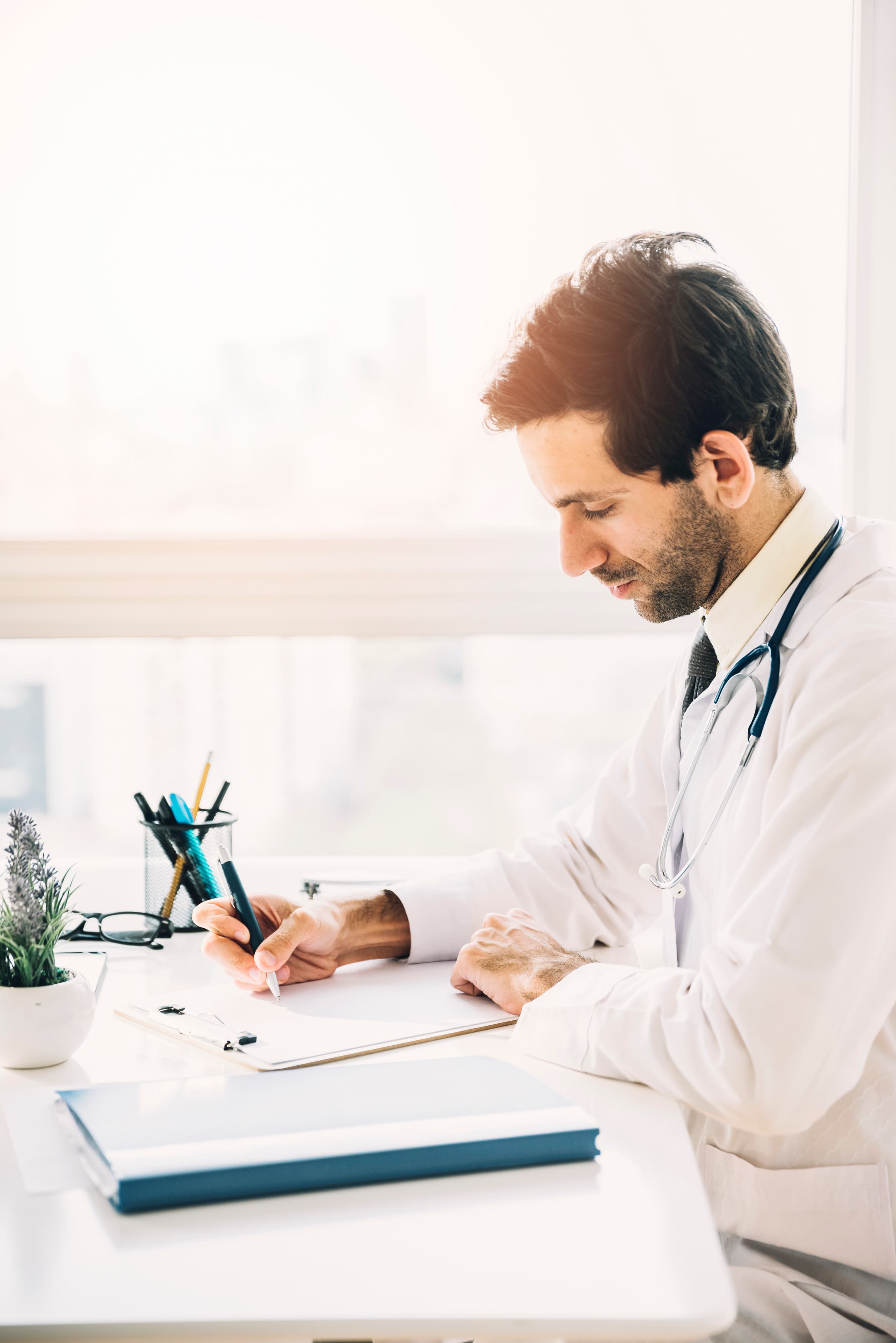 Doctor writing notes at a clinic desk
